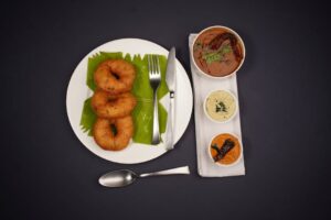 Delicious South Indian breakfast featuring medu vada and chutneys on a black background.